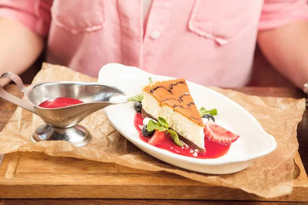 Fille mange dessert gâteau au fromage avec menthe sur l'assiette, bol de sauce — Photo