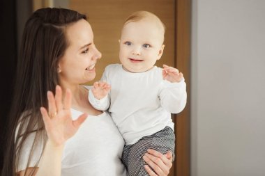 Onun bebek toddler dalga eli silah tutan kadın