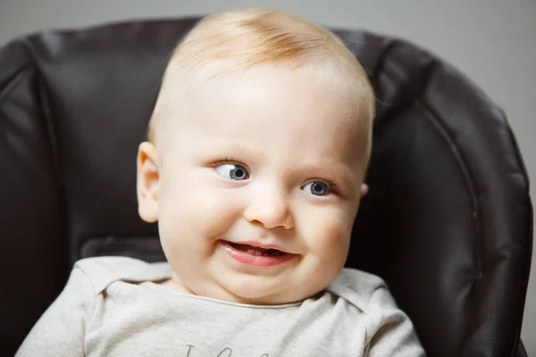 Baby in kinderstoel met interesse look en brede glimlach — Stockfoto