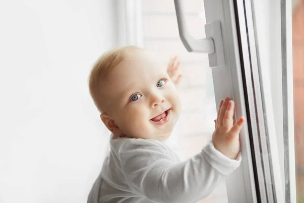 Uśmiechający się baby stojący w pobliżu otwartego okna, trochę malucha — Zdjęcie stockowe
