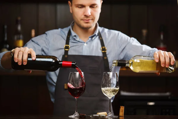 Чоловічий сомельє, що поливає червоне та біле вино в довгоногі келихи винограду — стокове фото