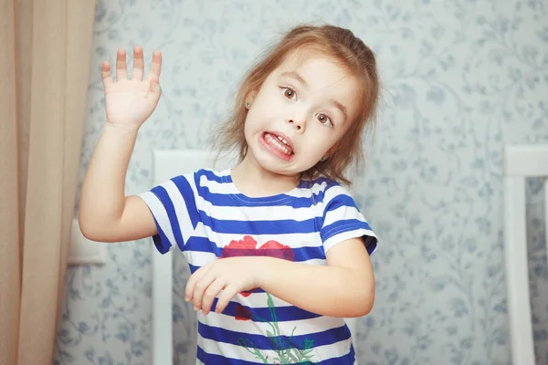 Bonito menina no listrado t-shirt faz engraçado rosto — Fotografia de Stock