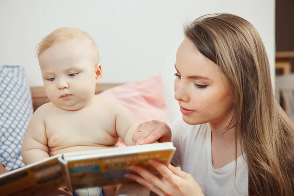 Madre leyendo un pequeño libro colorido infantil con cuentos de hadas . — Foto de Stock