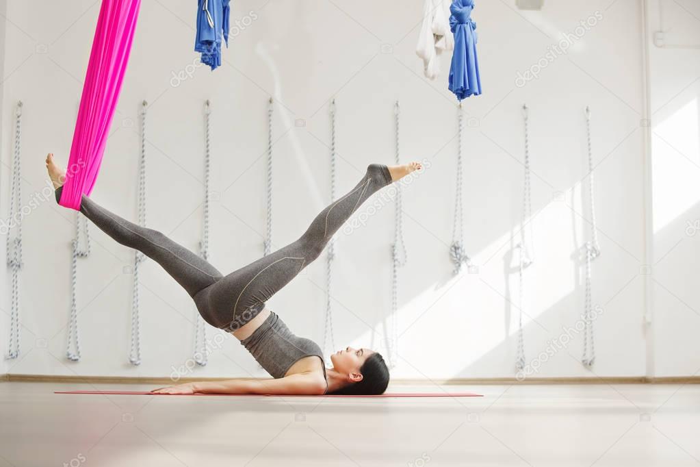 Side view of young woman doing antigravity yoga using hammock