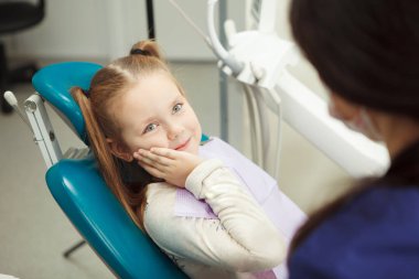 Üzgün Çocuk dişçi ofisinde oturur ve yanak tutar