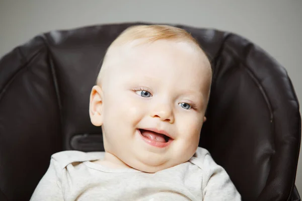 Baby in kinderstoel met interesse look en brede glimlach — Stockfoto