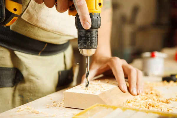 Wood boring drill in hand drilling hole in wooden bar — Stock Photo, Image