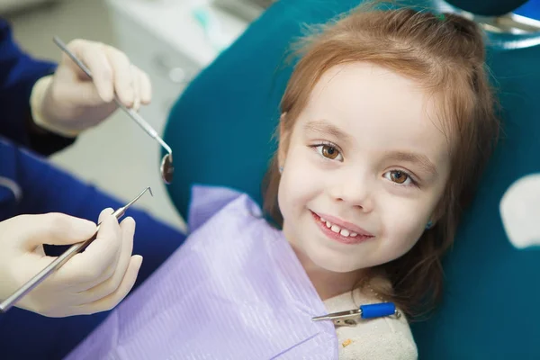 Criança com sorriso bonito senta-se na cadeira do dentista com guardanapo — Fotografia de Stock