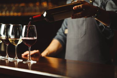 Barmen kırmızı şarabı bardaklara doldurur.