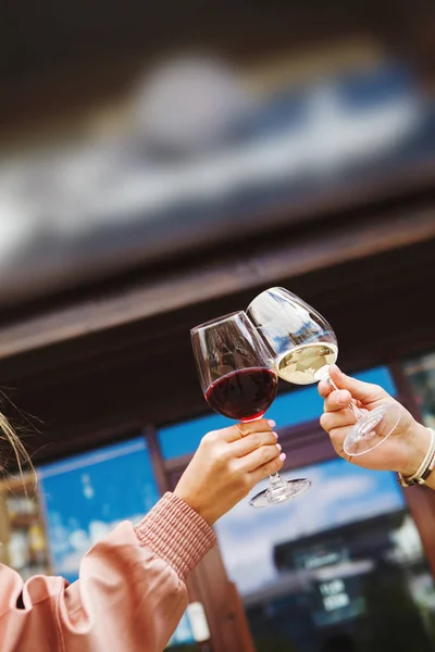 Two people clinking glasses with red and white wine