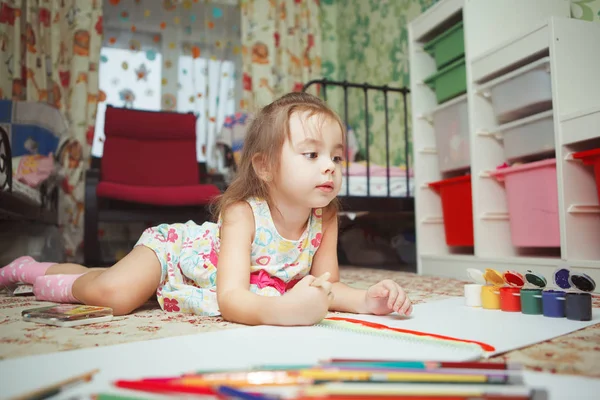 Malá holčička leží na ložnice podlahy a barvy obrázku — Stock fotografie
