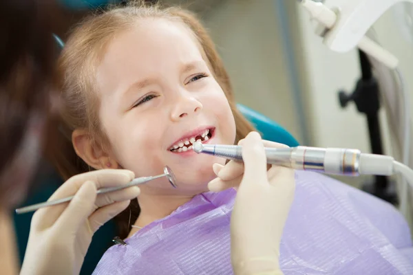 Criança sente dor de dente durante o procedimento de polimento em cadeira de dentista — Fotografia de Stock