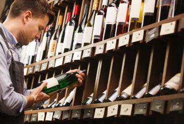 Düşünceli uzman şarap raflara arka plan üzerinde şarap yapımı.