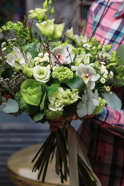 female hands holding green bouquet of Bronica, Brassica, Orchid, eustoma, hydrangea