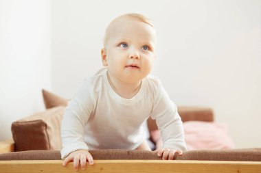 Gülümseyen bebek desteğine güvenerek kanepe ayakta.