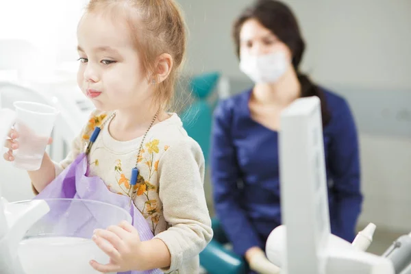 Child rinses out mouth and sits in dentist chair