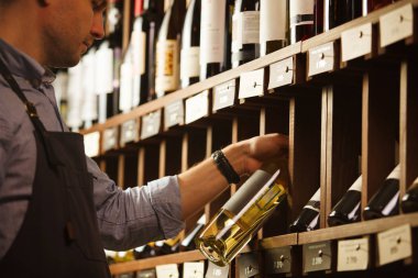 Düşünceli uzman şarap raflara arka plan üzerinde şarap yapımı.