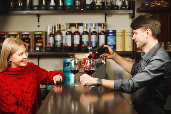 Bartender fills up two glasses with red wine from bottle