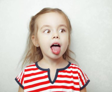 Küçük kız dilini çıkarır ve yana doğru görünüyor Adorablr