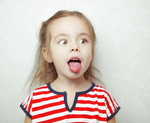 Adorável menina puxa a língua para fora e olha para o lado — Fotografia de Stock