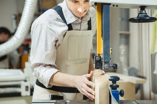 Dark-haired mens houdt van hout op de lintzaag — Stockfoto