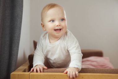 Gülümseyen bebek desteğine güvenerek kanepe ayakta.