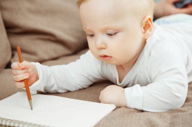 Genç bebek beraberlik öğrenme konsantre. Elinde kalem bebeğim