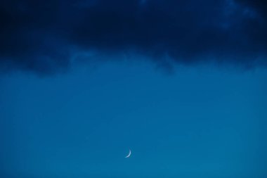 arka plan mavi gökyüzü ve kara bulutlar üzerinde ay. yeni bir döneme.