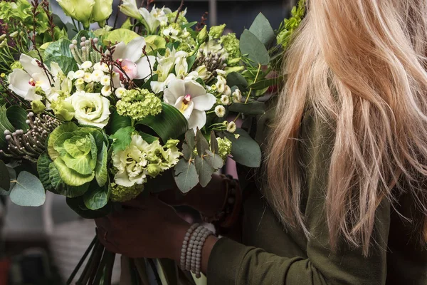 female hands holding green bouquet of Bronica, Brassica, Orchid, eustoma, hydrangea