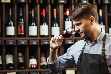 Arka planda bir şişe kırmızı şarap, erkek şarap garsonu içkinin değerini biliyor.