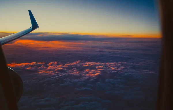 Bela vista do pórtico janela. a asa de um avião no fundo do céu por do sol com nuvens destacadas em laranja . — Fotografia de Stock