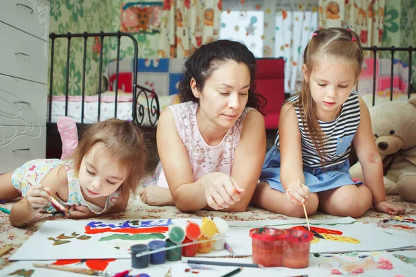Mamma e figlie dipingere quadri e sdraiati sul pavimento — Foto Stock