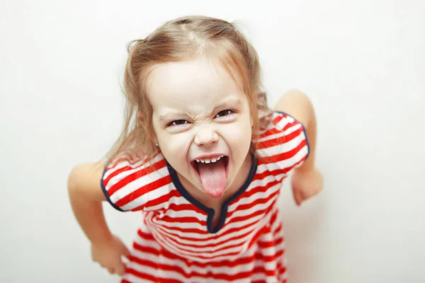 Enojada niña muestra su lengua en divertida mueca —  Fotos de Stock