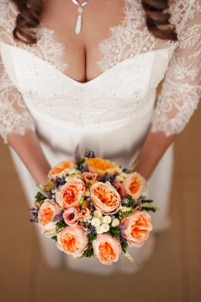 Belo buquê de laranja de casamento de rosas em mãos de noiva. close-up de atributo festivo em um evento familiar . — Fotografia de Stock