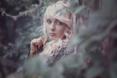 güzel sarışın ve yeşil bitki örtüsü arasında. doğal saç rengi ile sevimli bir kadın portresi.