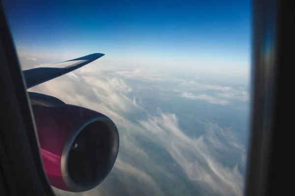 Ala de un avión con un motor rosa contra el cielo. nubes plumosas de portillo de ventana. estado de ánimo de vacaciones . —  Fotos de Stock