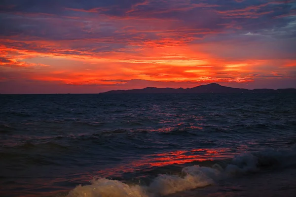 Puesta de sol roja en la playa. Playa con olas al atardecer . — Foto de Stock