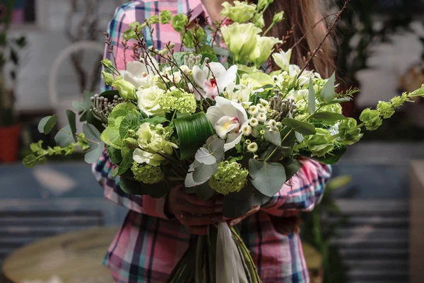 female hands holding green bouquet of Bronica, Brassica, Orchid, eustoma, hydrangea