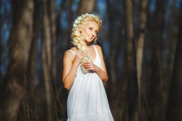Bella donna in abito bianco tira i suoi bei capelli in mezzo alla foresta primaverile . — Foto Stock