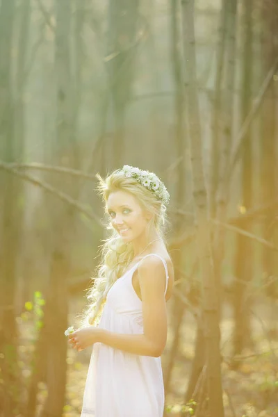 Frau in weißem Kleid und Kranz am Haar mitten im Frühlingspark. — Stockfoto