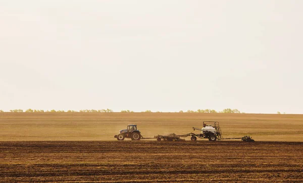 Ein Traktor mit Anhänger pflügt Feld für die Aussaat von landwirtschaftlichen Maschinen bereitet sich auf eine neue Ernte vor. — Stockfoto