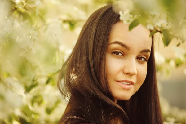 Jovem com pele limpa perto de uma macieira florescente. retrato de menina no parque de primavera . — Fotografia de Stock
