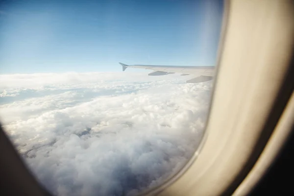 beautiful view from window porthole. the wing of the plane on a background of clouds and blue sky.