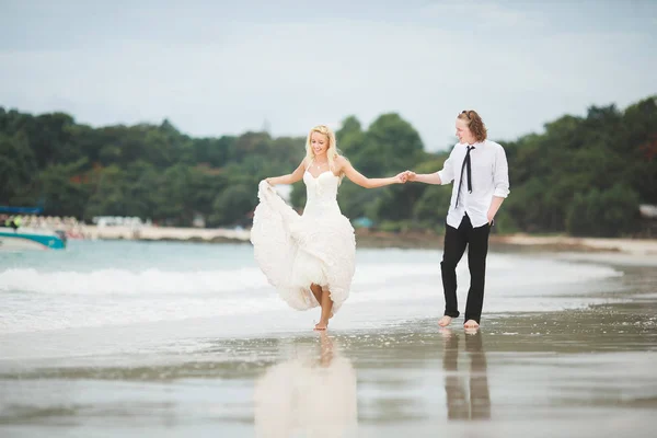 웨딩 드레스와 바다에 산책 하는 신랑의 신부 버려진된 해변에 결혼식. — 스톡 사진