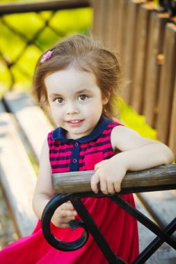 Güzel gözlü kız bankta oturur.