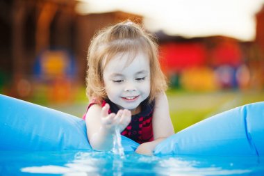 Kız ilgi ile su havuzu dokunur. Deniz kenarında bir meraklı çocuk.