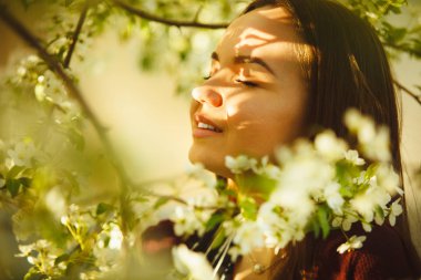 genç kadın çiçek açması ağaca kokluyor. Bahar parkta güzel kız.