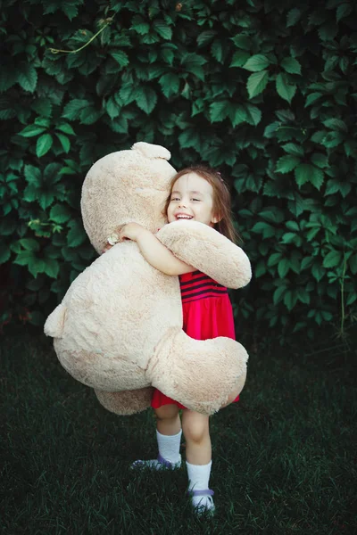 Menina feliz abraçando um grande urso de brinquedo . — Fotografia de Stock