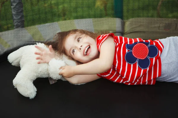 Criança alegre no trampolim com brinquedo macio . — Fotografia de Stock