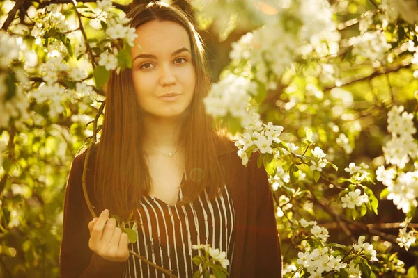 Jovem com pele limpa perto de uma macieira florescente. retrato de menina no parque de primavera . — Fotografia de Stock